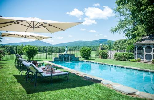 a woman sitting in lawn chairs next to a swimming pool at Glen Gordon Manor in Huntly