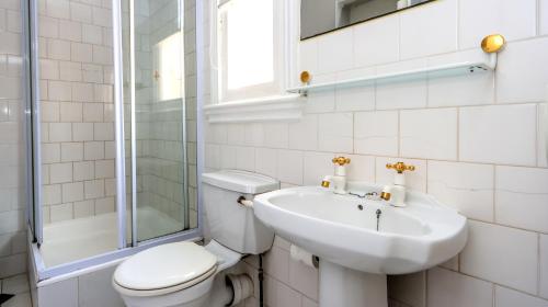 a white bathroom with a toilet and a sink at Sica's Guest House in Durban