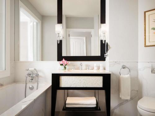 a bathroom with a sink and a tub and a mirror at Raffles Grand Hotel d'Angkor in Siem Reap