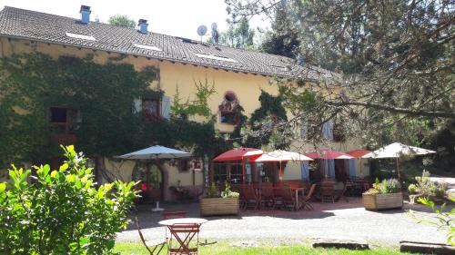 a building with tables and umbrellas in a yard at Auberge De La Charriole in Taintrux