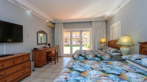 a bedroom with two beds and a desk and a television at Sica's Guest House in Durban
