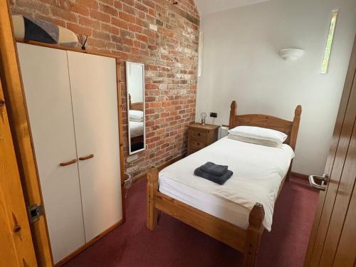 a small bedroom with a bed and a brick wall at Woodside Cottage in Newtown