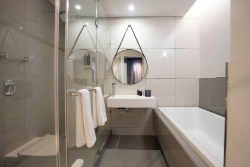 a bathroom with a tub and a sink and a mirror at The Capital on the Park in Johannesburg