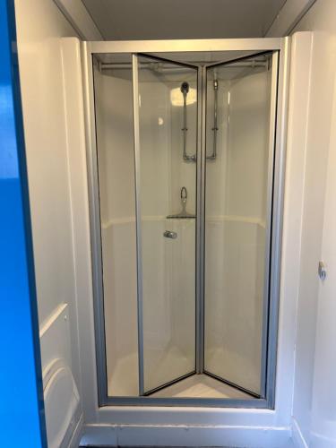 a glass shower in a bathroom with a toilet at Festival Glamping At The Drum - Glamping Village in Edinburgh