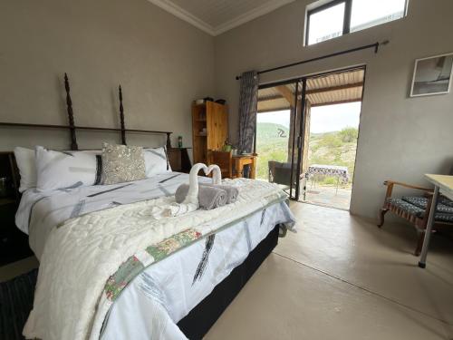 a bedroom with a bed with white sheets and a window at Shama Lodge - "Silent Sunsets" Duplex Cottage in Steytlerville