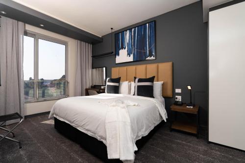 a bedroom with a large bed and a large window at The Capital on the Park in Johannesburg