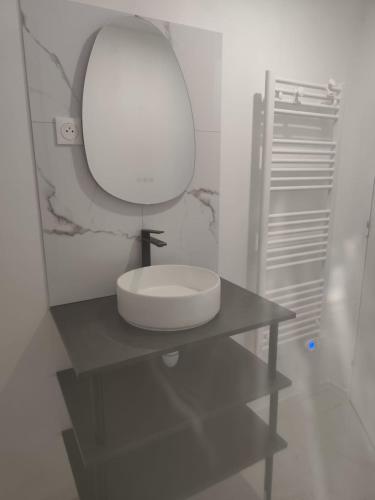 a white bathroom with a sink and a mirror at Logement à la ferme in Bréauté