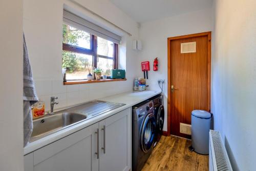 a kitchen with a sink and a washing machine at Garth Cottage in Gwaynynog