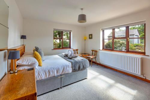 a bedroom with a bed and a desk and two windows at Garth Cottage in Gwaynynog
