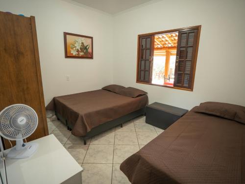 a bedroom with two beds and a window at Chácara Pimenta Vermelha in Socorro