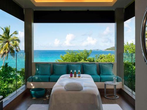 a room with a bed and a view of the ocean at Raffles Seychelles in Baie Sainte Anne