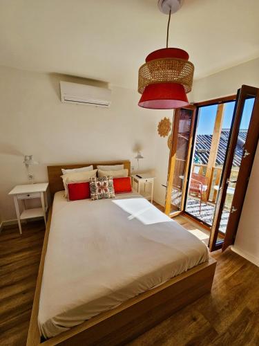 a bedroom with a large bed with a large window at Casa Laura João in Monsanto