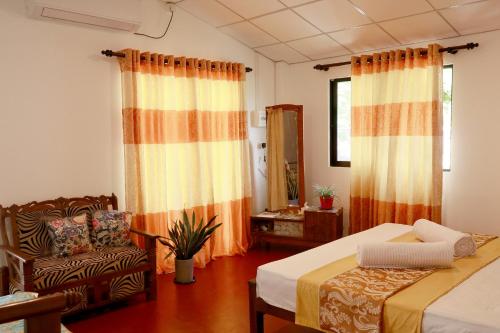 a bedroom with two beds and a chair and a window at Nature Beat villa in Mirissa