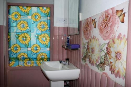 a bathroom with a sink and flowers on the wall at Nature Beat villa in Mirissa