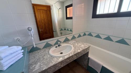 a bathroom with a sink and a mirror and a tub at Apartamentos Estrella De Mar in Roquetas de Mar