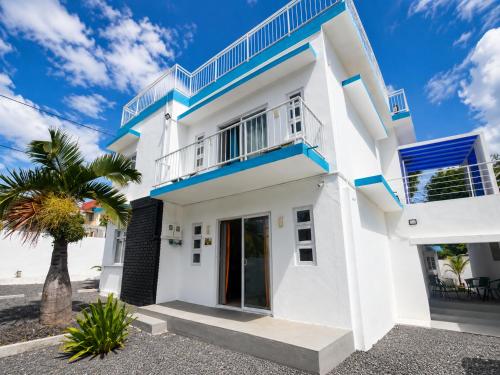 a white house with blue trim and a palm tree at Superbe Villa 6 personnes avec piscine - Le Sega in Pointe aux Sable
