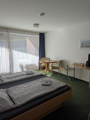 a hotel room with two beds and a table and chairs at Apartment 9, Zentrumsnah mit Pool und Balkon in Bad Essen