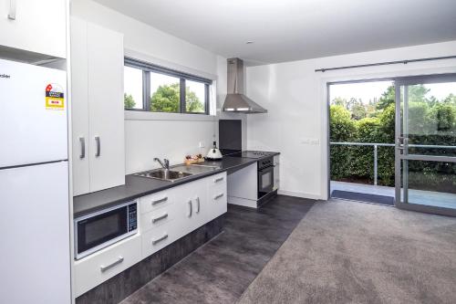 a kitchen with white cabinets and a large window at Black on Grey in Geraldine