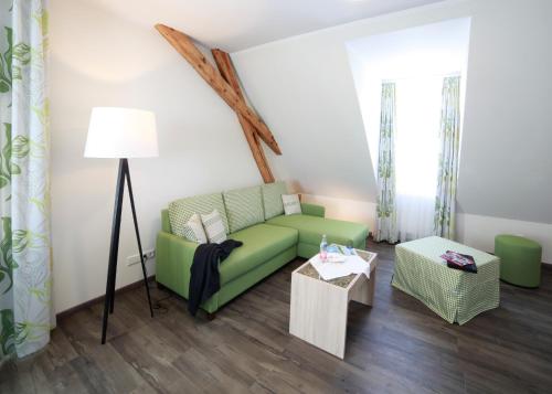 a living room with a green couch and a table at Schwarzwald Apartments Fürstenberg in Hüfingen