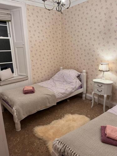 a bedroom with two beds and a table with a lamp at The Law House in Coldingham
