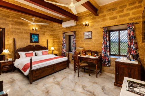 a bedroom with a bed and a desk in a room at WelcomHeritage Mohangarh Fort in Sodākor