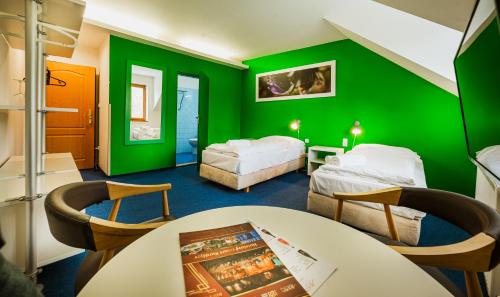 a green room with two beds and a table at Hotel Adina - resort Hotel Kurdějov & Art Wine Hall in Kurdějov