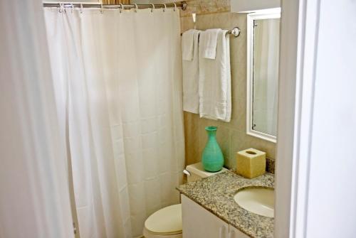 baño con cortina de ducha blanca y lavamanos en ZenBreak Silver Sands Villa 1, en Christ Church