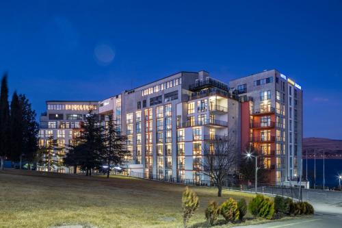 a large building with lights on in a park at GINO Seaside Tbilisi, Trademark Collection by Wyndham in Tbilisi City