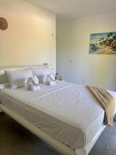 a large white bed with two stuffed animals on it at Pousada Villa Jodie in Fortim
