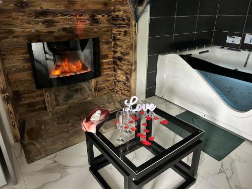a living room with a tub and a table and a fireplace at Le Petit Quiou in Le Quiou