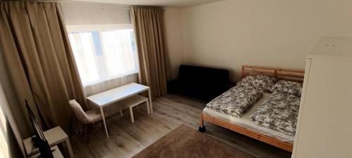 a bedroom with a bed and a desk and a window at Vila Kele in Tvrdošovce
