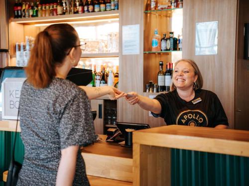 a woman standing at a bar talking to a woman at ibis Styles Lens Centre Gare in Lens