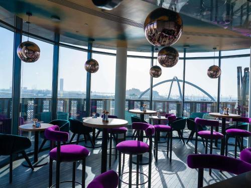 a restaurant with purple chairs and tables and a view of a stadium at ibis Styles Dubai Deira in Dubai