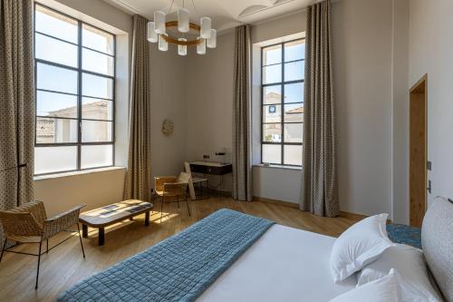 a bedroom with a bed and a desk and windows at Hôtel du Parc in Arles