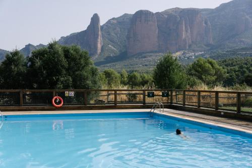 a person swimming in a pool with mountains in the background at Camping Armalygal in Murillo de Gállego