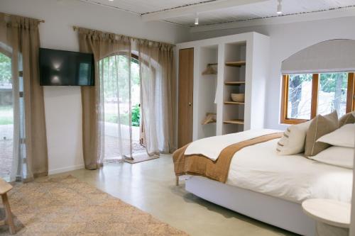 a white bedroom with a bed and a tv at The Oak Cottage in Wellington