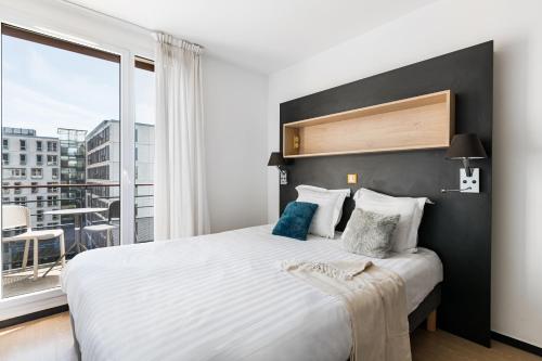 a bedroom with a large bed with a large window at Apparthotel Le Hüb Grenoble in Grenoble