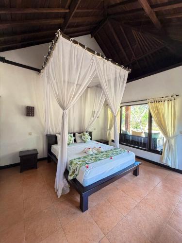 a bedroom with a bed with a canopy at Badini Homestay Pemuteran Bali in Pemuteran