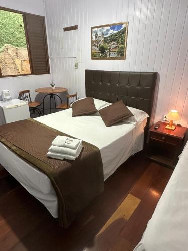 a bedroom with a large bed and a table at Pousada Mineira in Ouro Preto
