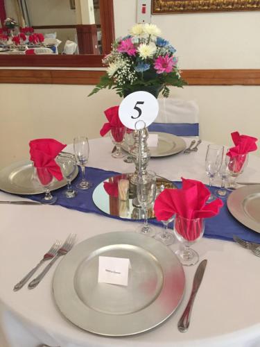 a table with white plates and a vase with flowers at Rayon Hotel in Negril