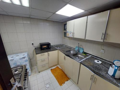 a small kitchen with a sink and white cabinets at Friends Hotel Apartments in Ajman 
