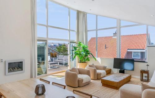 a living room with large windows and a tv at Villa By The Sea in Bergen aan Zee