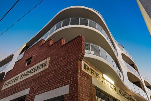 a brick building with a clock on the front of it at District Apartments Fitzroy in Melbourne