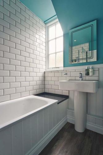 a white bathroom with a tub and a sink at The Old Success Inn in Sennen Cove