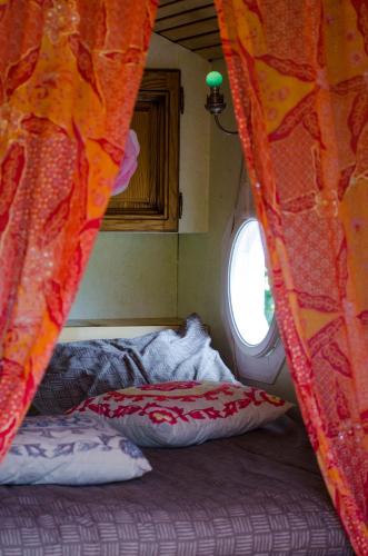 a bedroom with a bed with a curtain and a window at Ecrin du Ségala - Roulotte insolite in Tauriac-de-Naucelle
