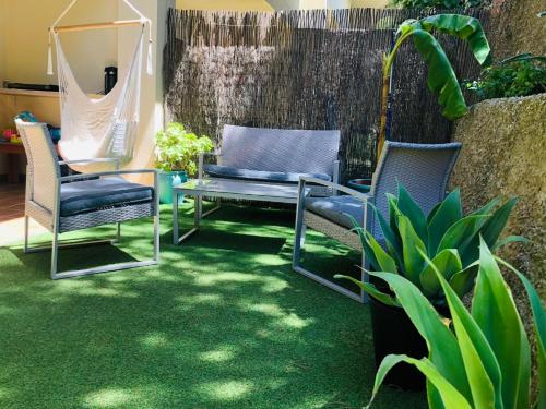 a patio with three chairs and a hammock on the grass at Marta Beach House - Caños De Meca in Los Caños de Meca