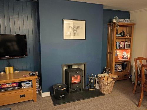 a living room with a fireplace and a tv at Broom Cottage in Newtonmore