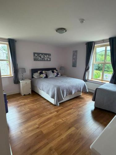 a bedroom with a bed and wooden floors and windows at The Twelve Oaks in Kenmare
