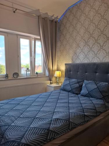 a bedroom with a blue and white bed with windows at Kameralny Apartament w Centrum in Szczytno