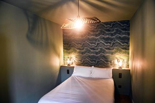 a bedroom with a bed with two lights on it at Les Gens Heureux Appartement GLAZ in Paimpol